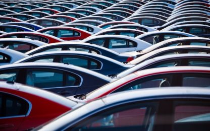 rows of automobiles/cars parked on a large holding lot after import to the USA