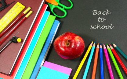Back to school concept with stacked books, red apple, school supplies and color pencils.